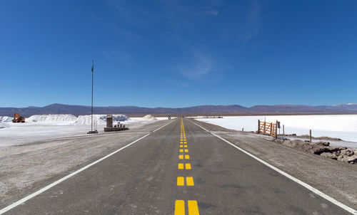 Road leading towards mountains against sky