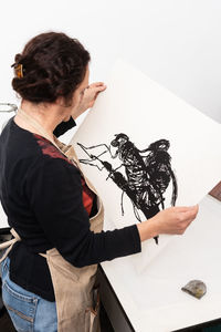 High angle view of woman holding paper while standing on table