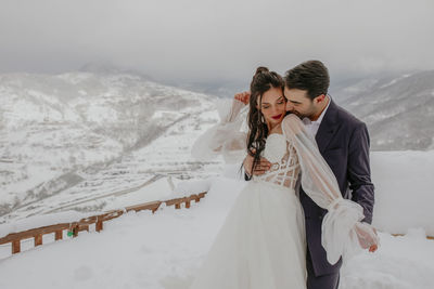 Couple kissing on snow covered landscape