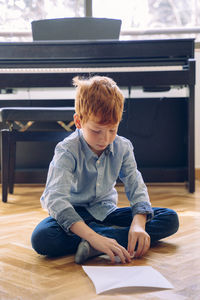 Full length of boy sitting on flooring