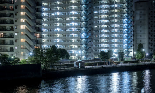 Illuminated buildings by canal in city at night