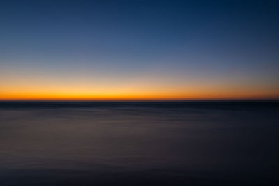 Scenic view of sea against clear sky at sunset