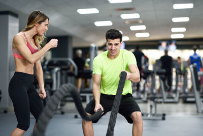 Trainer assisting man exercising in gym