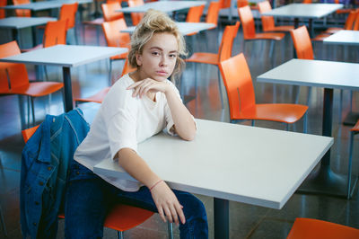 Portrait of young woman sitting on chair in classroom