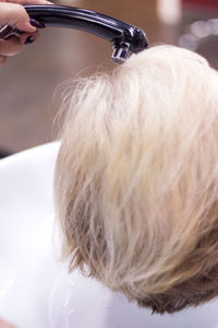 Cropped hand of woman washing hair at hair salon