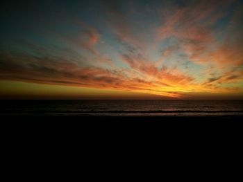 Scenic view of sea against dramatic sky during sunset