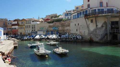 Boats moored in sea against buildings in city