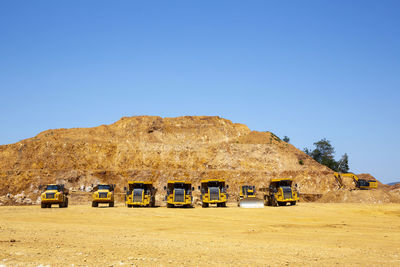 Cars on road by land against clear blue sky