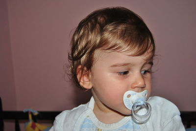 Cute baby boy sucking pacifier at home