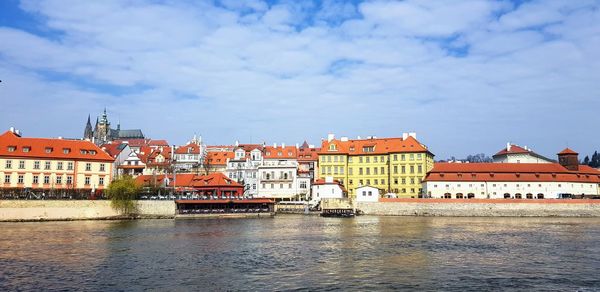 Buildings by river against sky in city