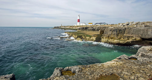 Lighthouse by sea against sky