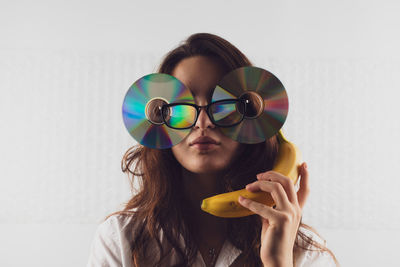 Woman wearing compact disc while holding banana