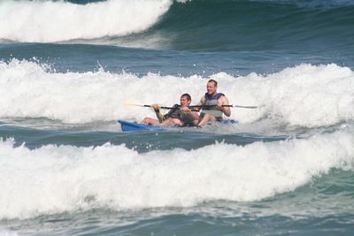 People surfing in sea against clear sky