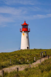 Lighthouse on field against sky