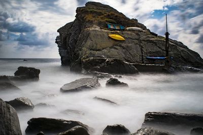 Boats on rock formations in sea against sky