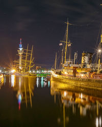 Boats moored at harbor in city at night