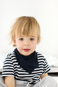 Portrait of cute boy sitting on bed at home