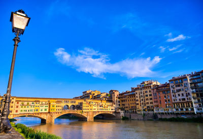 Low angle view of bridge over canal by buildings against sky