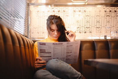 Young woman reading menu while sitting in restaurant