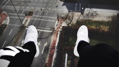 Low section of man sitting over street in city