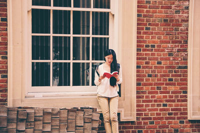 Portrait of woman standing against window