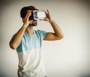 Young man wearing virtual reality simulator while standing at home