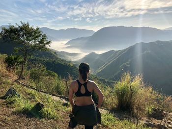 Rear view of woman looking at mountains against sky