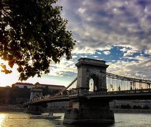 Bridge over river against cloudy sky