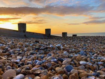 Rocks on beach against sky during sunset