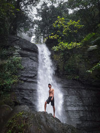 Rear view of man standing in waterfall