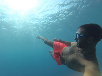 Side view of shirtless man swimming in sea