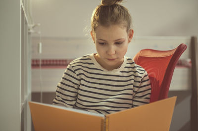 Portrait of young woman reading book at home