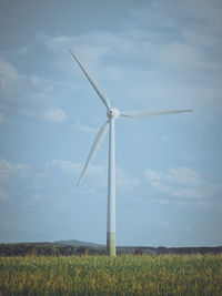 Windmills on field against sky