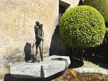 Statue on rock against wall