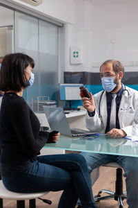 Doctor wearing mask examining patient in clinic