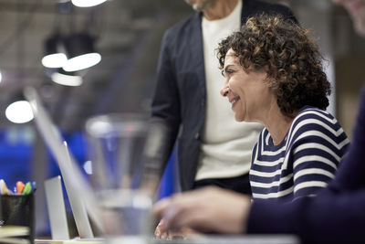 Smiling senior businesswoman with colleagues at conference table in meeting