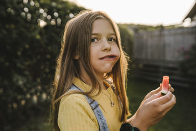 Portrait of woman with mobile phone standing outdoors