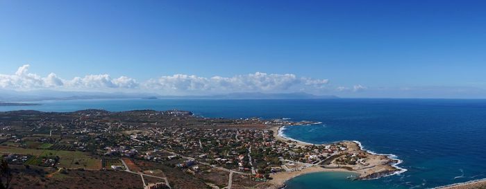 Aerial view of town by sea against blue sky