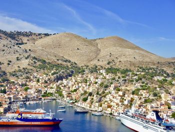 Boats moored in sea by city against sky