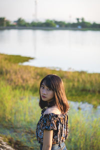 Portrait of beautiful young woman standing at lake