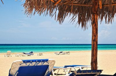 Chairs and table at beach against sky