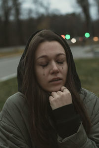 Crying young woman with running mascara on the street in twilight