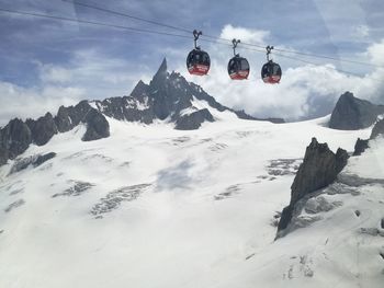 Overhead cable car on snowcapped mountains against sky