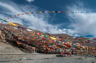 Multi colored flags hanging on mountain against sky