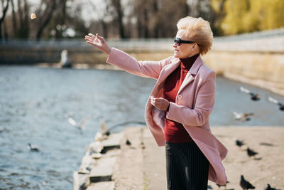 Smiling senior woman standing by lake