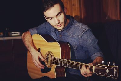 Handsome man playing guitar at home