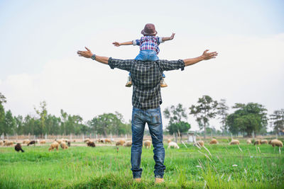 Rear view of man standing on field against sky