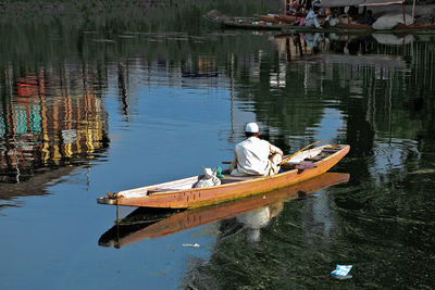 Rearview of kashmiri man sitting on a boat in the lake for fishing.