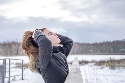 Rear view of woman with umbrella against sky during winter