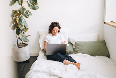 Portrait of woman sitting on bed at home